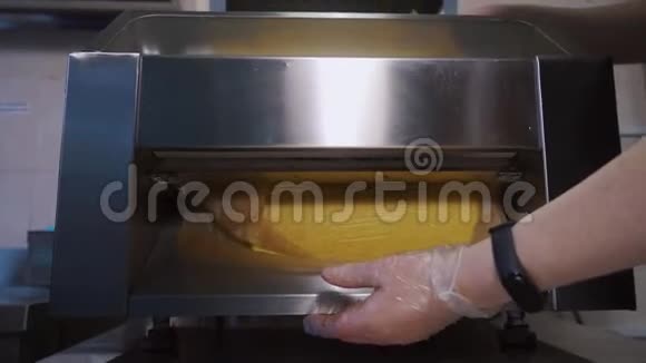 做面团片在一台特殊的烹饪机器上滚动面团视频的预览图