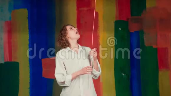情人节美女天使女孩带着红色的气球笑着彩色彩虹的背景快乐的天使女性快乐视频的预览图