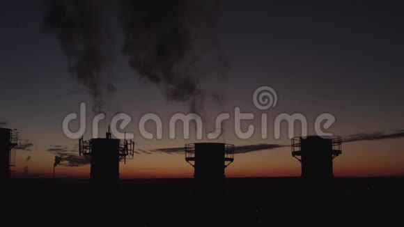 夕阳和城市背景下高高的烟囱浓烟高高升起五座冷却塔的剪影视频的预览图