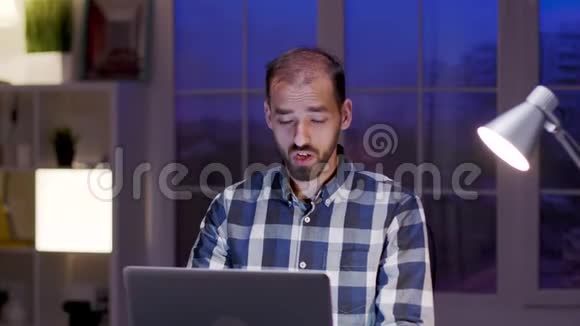 一位在笔记本电脑上打视频电话时穿着衬衫的商人视频的预览图