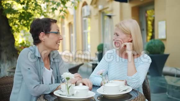 女朋友在街头咖啡馆玩得很开心说着笑坐在桌子上视频的预览图