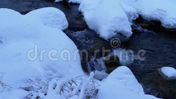 冬林中的山溪山河在冬季的冰雪中流淌视频的预览图