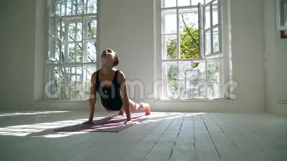 苗条的白种人女人站在大房间里的垫子上练习瑜伽女孩慢慢地弯曲了她的身体精神视频的预览图