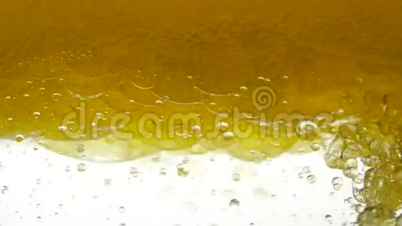 沉淀罐中的金色液体会放出气泡葵花籽油与亚麻籽和气泡结构混合视频的预览图
