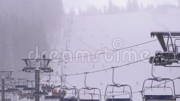 滑雪场滑雪电梯滑雪者在滑雪椅电梯上爬上滑雪坡伴着降雪视频的预览图