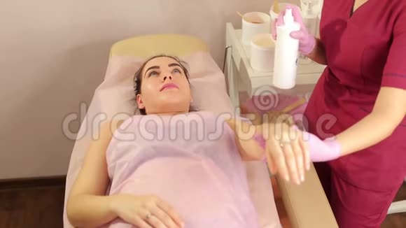 美容师在脱毛前一个年轻女孩的手上撒上滑石粉视频的预览图
