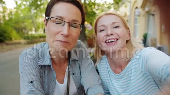 慢动作女士在街边咖啡馆打视频电话挥手视频的预览图