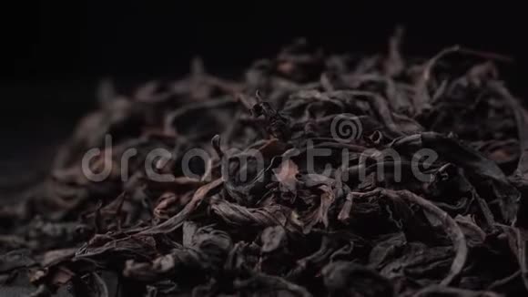 芬芳的红茶叶子在黑桌上旋转美丽的绿茶躺在桌子上相机绕着它旋转视频的预览图