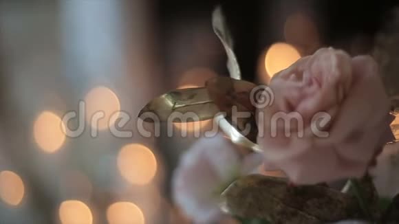 在闪烁的蜡烛的背景下在一个特写镜头中花瓶里美丽的鲜花白色和粉红色玫瑰视频的预览图