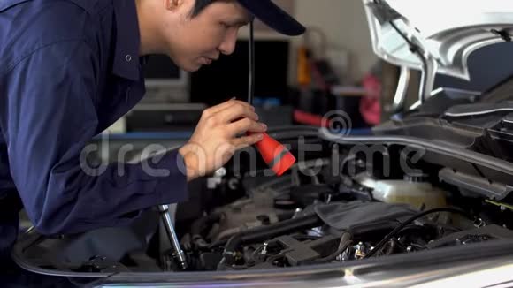 男性机械师拿着手电筒检查汽车发动机问题视频的预览图