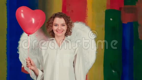 年轻的天使女人有着情绪化的脸和心脏气球派对女孩有心形空气的美丽天使女孩视频的预览图