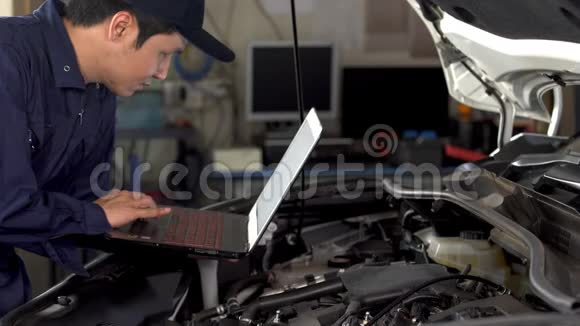 男性机械师在修理汽车时使用笔记本电脑视频的预览图