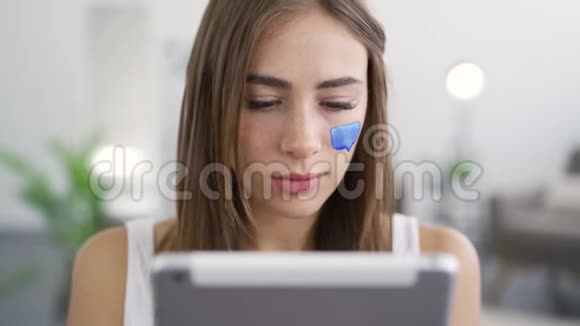 特写肖像年轻可爱的女人坐在家里看着平板电脑微笑女孩的留言框视频的预览图