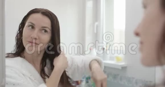 女人洗澡后用刷子在浴室刷头发拍摄红色史诗视频的预览图