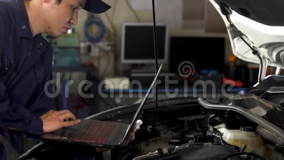 男性机械师在修理汽车时使用笔记本电脑视频的预览图