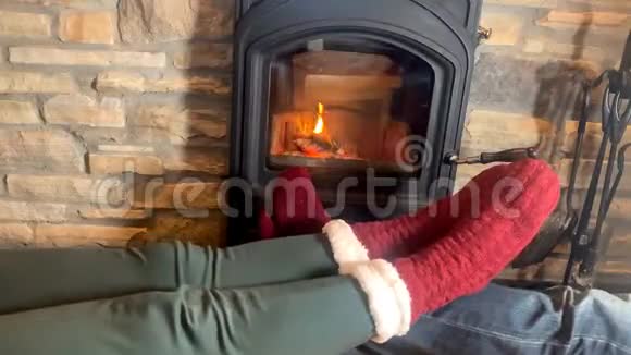 男人和女人躺在滚烫的壁炉旁双腿穿着红袜向火堆伸展冬季放松的概念视频的预览图