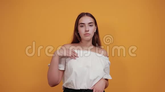 强壮的年轻女子展示着肌肉看上去很高兴被隔离在橙色的墙上视频的预览图