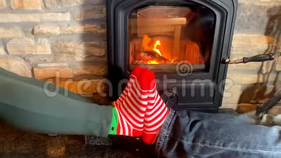 穿着条纹袜子的男性和女性的双腿在燃烧的壁炉的炉火旁跳舞圣诞节的概念视频的预览图