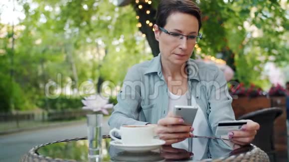 成熟的女商人使用智能手机用信用卡付款视频的预览图