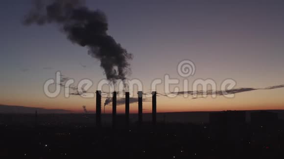 在一个大城市和日落的背景下五个冷却塔的剪影在吸烟的时候美丽的日落视频的预览图