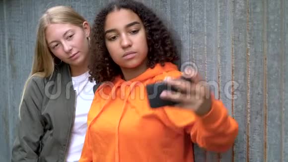 慢动作视频剪辑美丽的金发女孩和混合种族青少年年轻妇女使用他们的智能手机社交媒体视频的预览图
