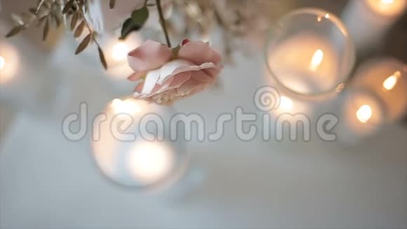白色粉红色的玫瑰花放在眼镜上方的花瓶里上面有蜡烛房子前面是俯视的美丽的花朵视频的预览图