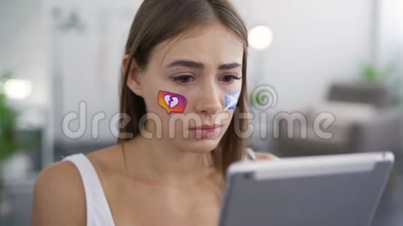 年轻女子手中拿着平板电脑悲伤地看着相机的肖像社会媒体图标视频的预览图