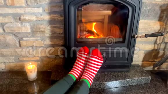 女人坐在滚烫的壁炉旁双腿穿着红袜向火堆伸展冬季放松的概念视频的预览图