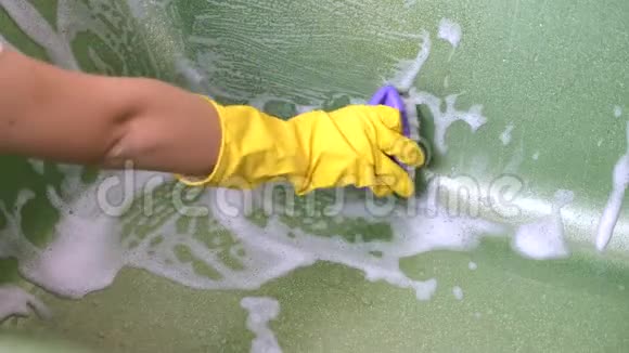 女人用刷子在绿光浴中清洁黄色手套视频的预览图
