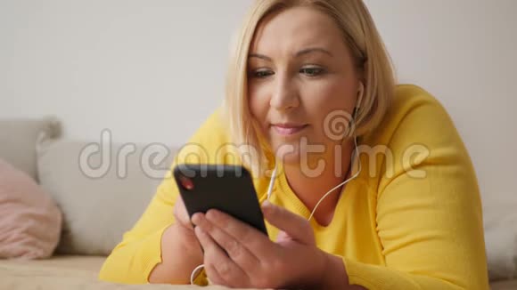 年轻女子躺在家里的床上在智能手机上进行视频聊天视频的预览图