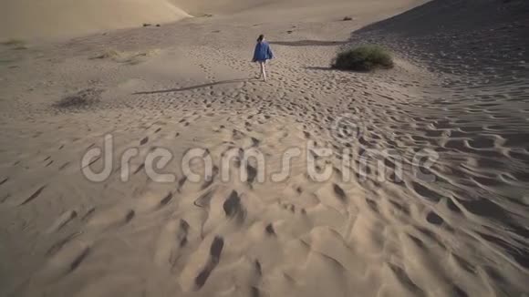 一个孤独的年轻女子在干旱的夏天穿过干燥的沙漠视频的预览图