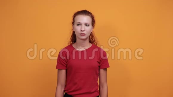 穿着红色衬衫的无聊的年轻女士把手放在下巴上想着问题视频的预览图