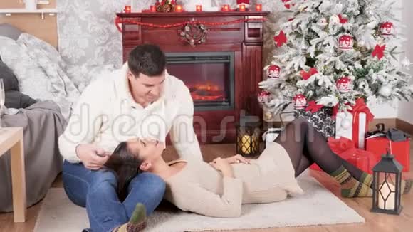圣诞前夜一对放松的夫妇躺在壁炉旁边的地板上视频的预览图