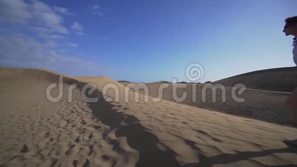一个女模特在沙漠中走上沙丘慢动作广角日落MaspomasDunes视频的预览图