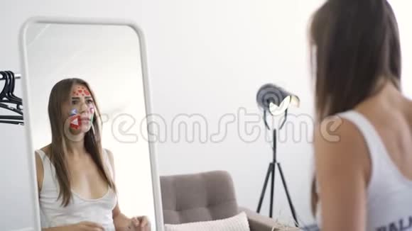 年轻女子的后视图她的脸上有五颜六色的社交媒体图标看着镜子尖叫着视频的预览图