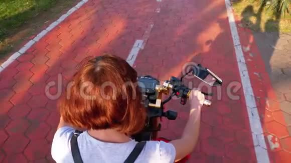 在度假小镇上女人骑着一辆电动滑板车在一条红色的自行车道上骑着棕榈树视频的预览图