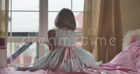 白种人女孩坐在床上看着肩膀上的摄像机穿着蝴蝶服装的孩子视频的预览图
