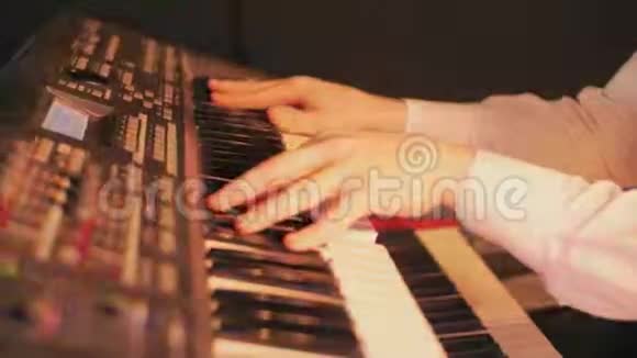 钢琴家的特写他的手在蓝色灯光的舞台上用键盘弹奏一首歌视频的预览图