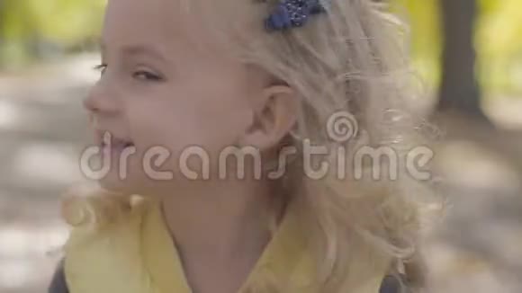 一个金发棕色眼睛的小可爱女孩的肖像微笑着摇头快乐的白种人儿童视频的预览图