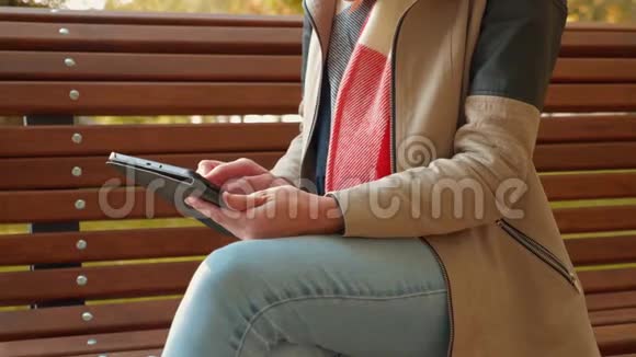 坐在长凳上的女孩在平板电脑上在线订购并在送货时立即收到视频的预览图