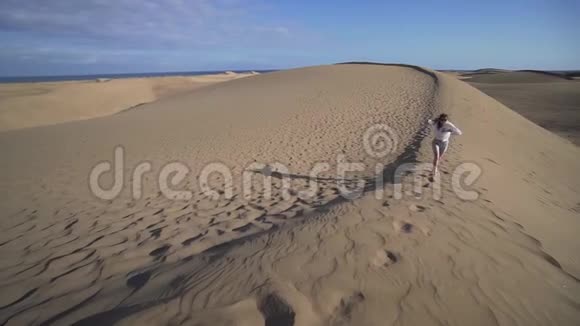 沙漠中的一个女人享受她的假期微笑着跑上沙滩视频的预览图