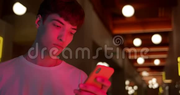穿着白色T恤的年轻时尚男士用智能手机在站在未来派新生儿的社交网络中聊天视频的预览图