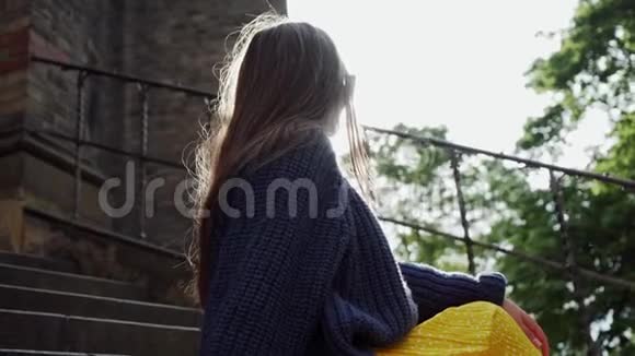 戴太阳镜的女孩坐在阳光下的石阶上她微笑着画像视频的预览图