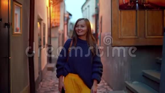 幸福的女孩沿着古老城市狭窄的晚街散步前景肖像视频的预览图