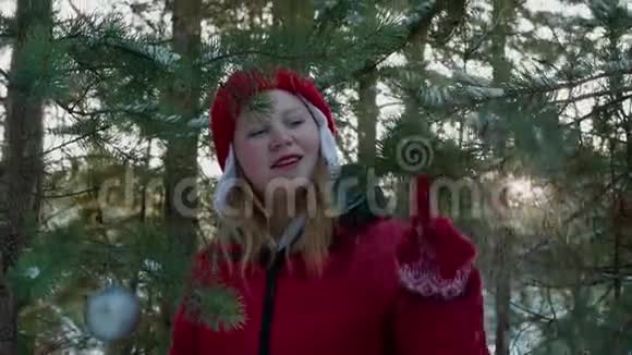快乐的女孩在冬天的森林里玩雪松枝年轻女子触摸针叶树枝视频的预览图