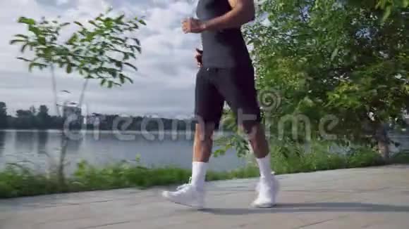 肌肉发达的非洲男人沿着城市湖泊奔跑视频的预览图