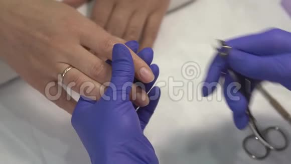 专业的美甲师在手套上剪下指甲上的皮肤然后涂上清漆视频的预览图
