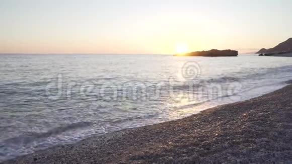 亚得里亚海美丽的日落卵石海岸海滩上的石头在水里摇晃太阳落山海浪视频的预览图