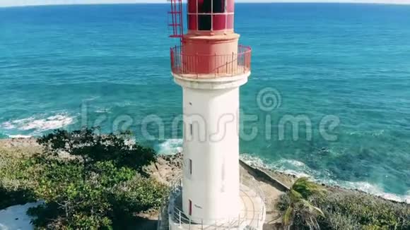 夏天白色的灯塔靠近蓝色的大海阳光明媚的一天灯塔上的鸟瞰图视频的预览图