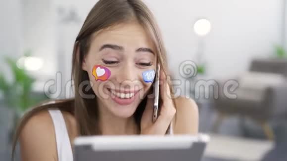 年轻美丽的女人的肖像脸上画着社交媒体的图标拿着平板电脑在电话中交谈视频的预览图